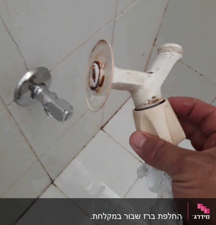 יד מחזיקה ברז ישן עם חלודה